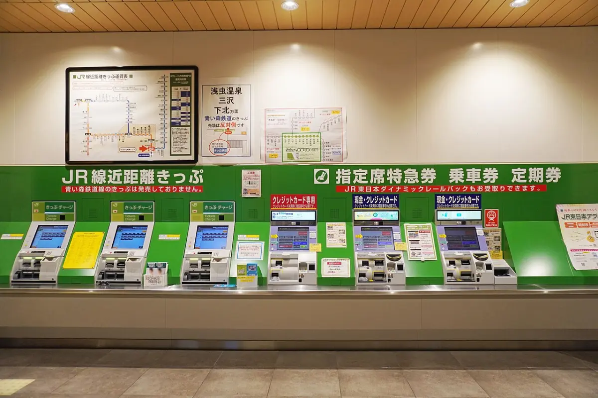 Row of JR East ticket vending machines with a fare map above them