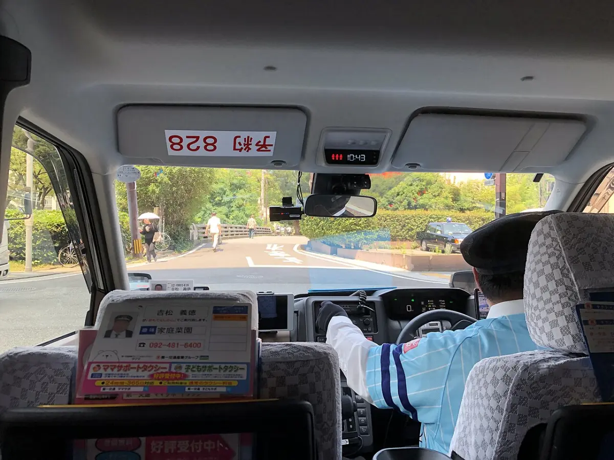 Rear-seat view inside a Toyota JPN Taxi, showing the back seats and the driver's area