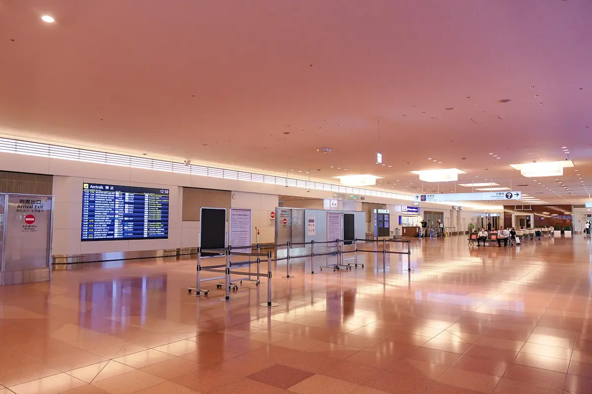 Quiet arrival lobby of Haneda Airport Terminal 3 with a flight information board