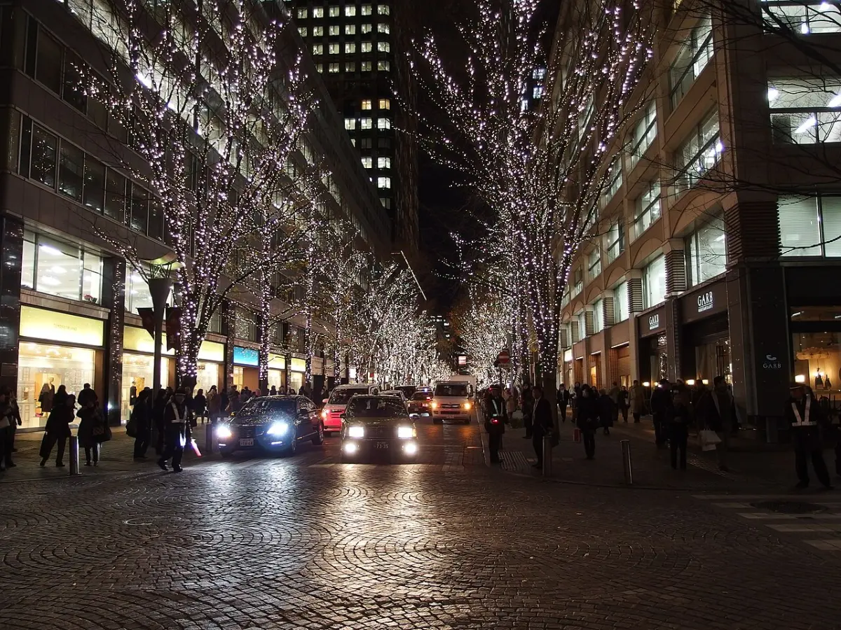 Trees wrapped in Christmas lights along a cobblestone street in Marunouchi at night