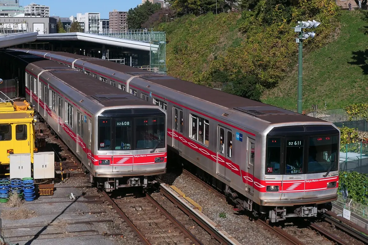 Two red-striped Tokyo Metro Marunouchi Line trains passing at Yotsuya Station