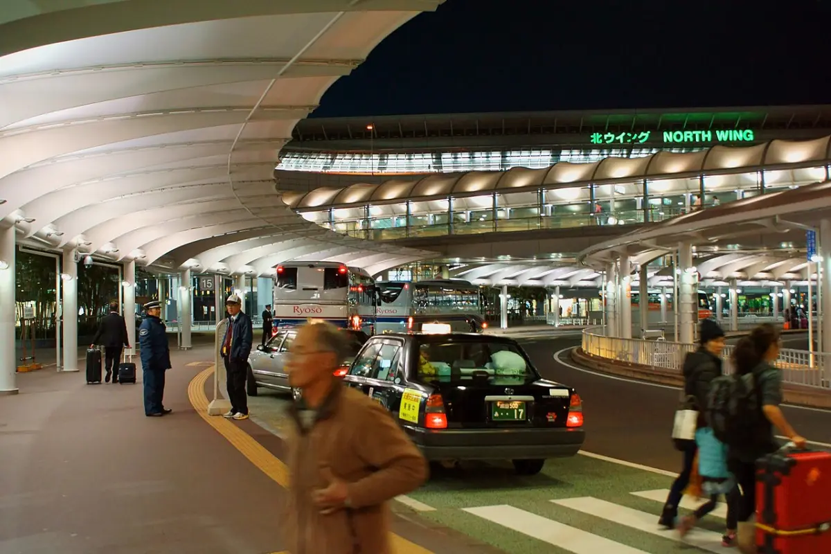 Narita Airport Terminal 1 North Wing curbside at night with taxis, buses and travelers with luggage