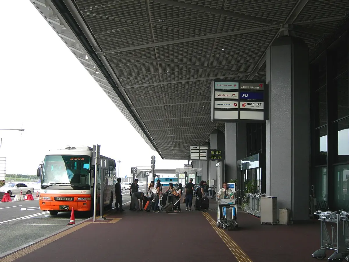 Airport Limousine bus at the Narita Airport South Wing curb with travelers and luggage carts