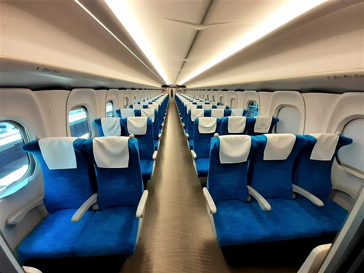 Ordinary car of an N700S Shinkansen with rows of three and two blue reserved seats